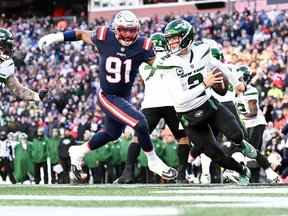 Le quart-arrière des Jets de New York, Zach Wilson, court avec le ballon sous la pression de l'ailier défensif des Patriots de la Nouvelle-Angleterre Deatrich Wise Jr. pendant la seconde moitié au stade Gillette.