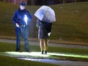 Un policier de Laval arrête une femme marchant sur le terrain de l'école après une fusillade dans un parc situé à côté du Collège Montmorency à Laval le vendredi 11 novembre 2022.