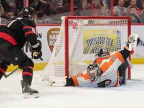 Le gardien des Flyers de Philadelphie Carter Hart (79) effectue un arrêt devant le centre des Sénateurs d'Ottawa Derick Brassard (61) en première période au Centre Canadian Tire samedi soir.