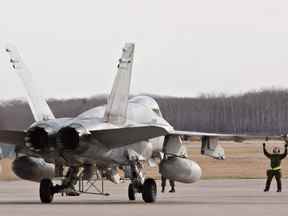 Des militaires guident un CF-18 Hornet en position à la BFC Cold Lake, à Cold Lake, en Alberta.