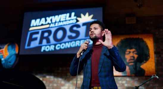 Maxwell Frost speaking on stage in a blue suit, gesturing with left hand