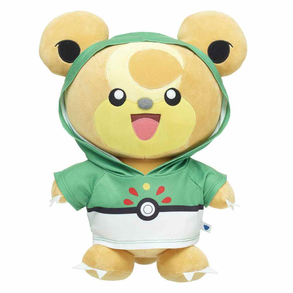 Une peluche Teddiursa portant un sweat à capuche vert et blanc ressemblant à une Poké Ball sur fond blanc.