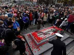 Des gens déposent des coquelicots sur la Tombe du soldat inconnu après la cérémonie du jour du Souvenir au Monument commémoratif de guerre du Canada à Ottawa, le vendredi 11 novembre 2022.