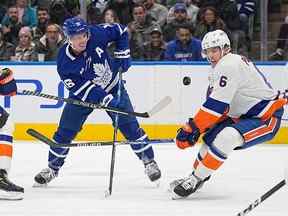 Ryan Pulock des Islanders de New York et Mitchell Marner des Maple Leafs (à gauche) se battent pour la rondelle lors de la première période au Scotiabank Arena le lundi 21 novembre 2022.