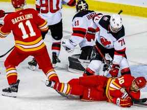 Les Flames de Calgary Jonathan Huberdeau est renversé sur la glace par Jonas Siegenthaler des Devils du New Jersey lors d'un match de hockey de la LNH au Scotiabank Saddledome de Calgary le samedi 5 novembre 2022. AL CHAREST/POSTMEDIA