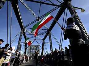 Les manifestants agitent les couleurs du drapeau de l'Iran alors qu'ils participent à une manifestation mondiale 