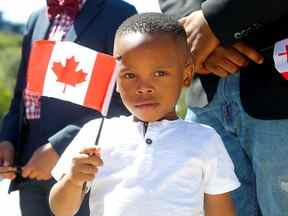 Brian Egbe agite un drapeau lors d'une cérémonie publique de citoyenneté au Calgary Stampede le 11 juillet 2022.