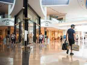 Un client sort d'un magasin contenant plusieurs sacs à provisions dans le centre commercial Sherway Gardens à Toronto.