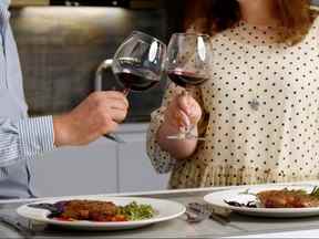 Heureux couple profitant d'un dîner romantique à la maison avec un steak rôti et du vin rouge