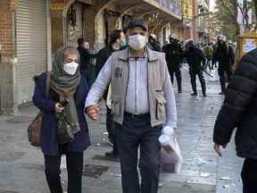 Des gens marchent devant des magasins fermés du Grand Bazar de Téhéran, en Iran, alors que la police anti-émeute patrouille sur les lieux de la manifestation, le 15 novembre 2022.