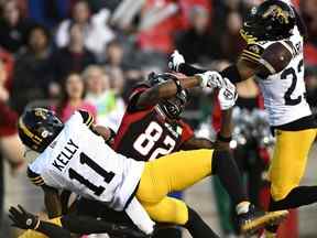 Kameron Kelly (à gauche) et Richard Leonard des Tiger-Cats de Hamilton empêchent le Siaosi Mariner des Redblacks d'Ottawa d'attraper la prise à la Place TD, le 29 octobre 2022.