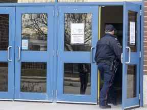 Un policier de Londres se tient à la porte de l'école secondaire HB Beal après avoir poignardé dans sa cafétéria le lundi 21 novembre 2022. (Mike Hensen/The London Free Press)