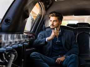 Homme d'affaires en limousine avec coupe de champagne, profitant