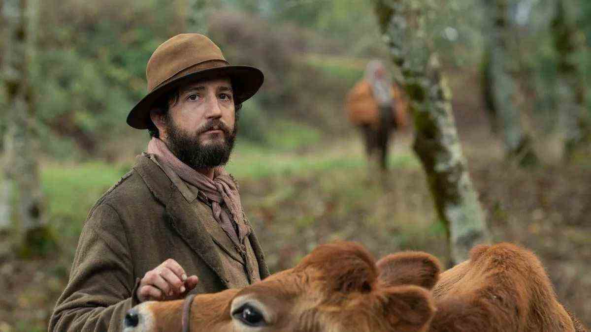 John Magaro porte une tenue du nord-ouest du Pacifique du XIXe siècle tout en caressant une vache très douce dans First Cow.