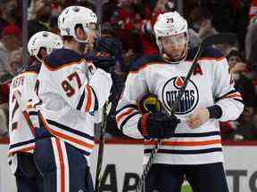 Connor McDavid (97) et Leon Draisaitl (29) des Oilers d'Edmonton discutent lors d'une revue vidéo en troisième période contre les Devils du New Jersey au Prudential Center le 31 décembre 2021 à Newark, New Jersey.