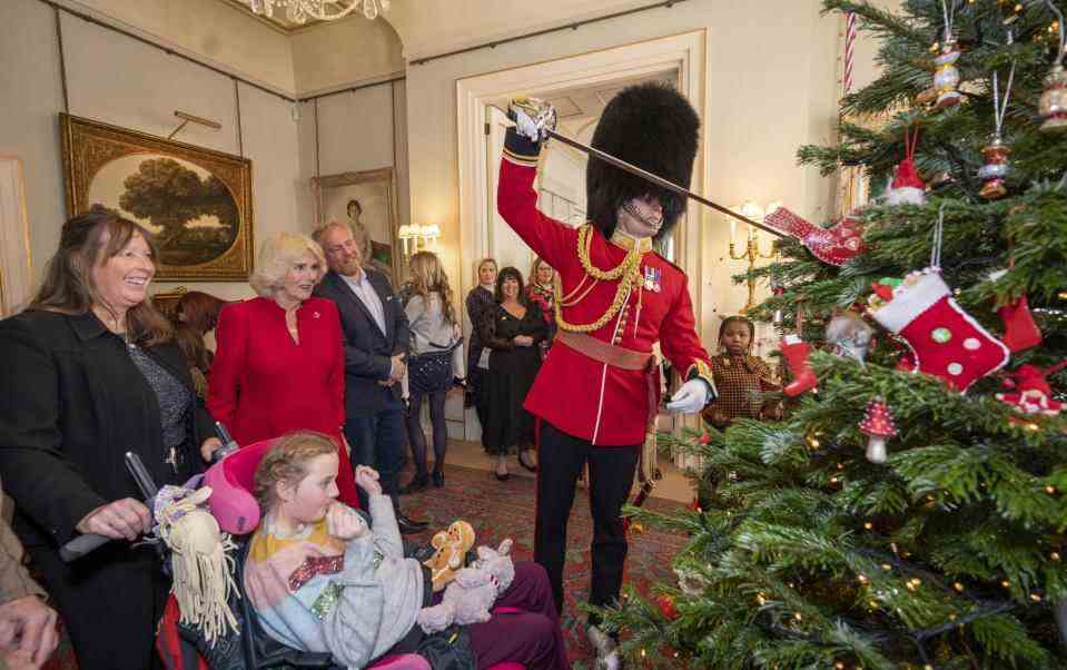 Un écuyer en peau d'ours et en uniforme de garde a utilisé la pointe de son épée pour soulever des décorations sur l'arbre - Getty Images Europe