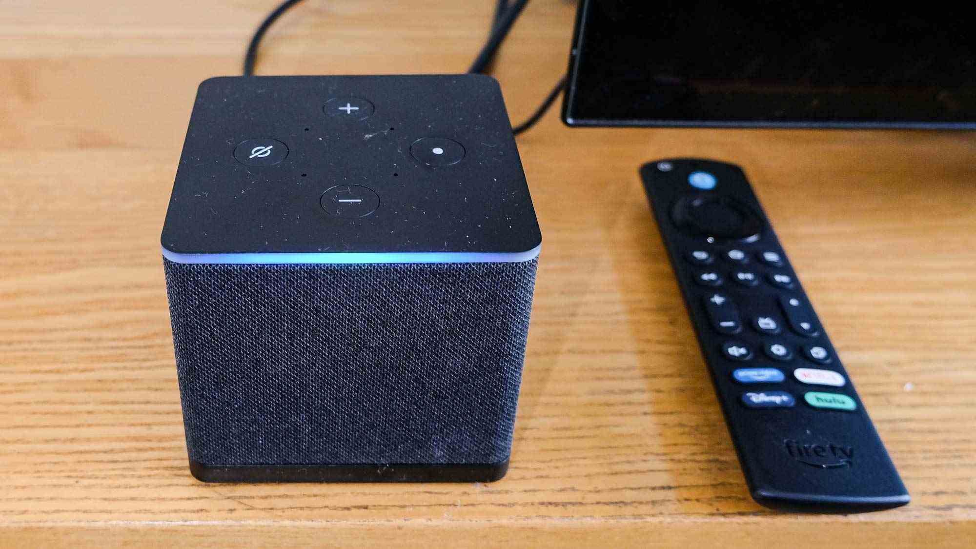 Un gros plan du Fire TV Cube (2022) avec sa barre Alexa bleue brillante et sa télécommande à droite