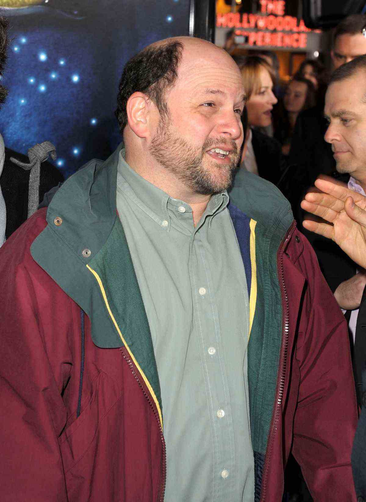 Jason Alexander portant un coupe-vent rouge et vert à la première d'Avatar