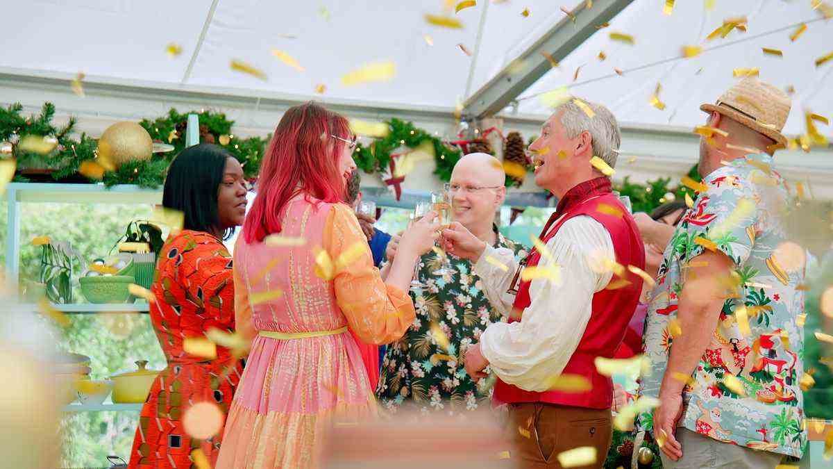 Les concurrents du spécial vacances de The Great British Bake Off, dans sa troisième saison, debout autour d'une table alors que des confettis tombent.