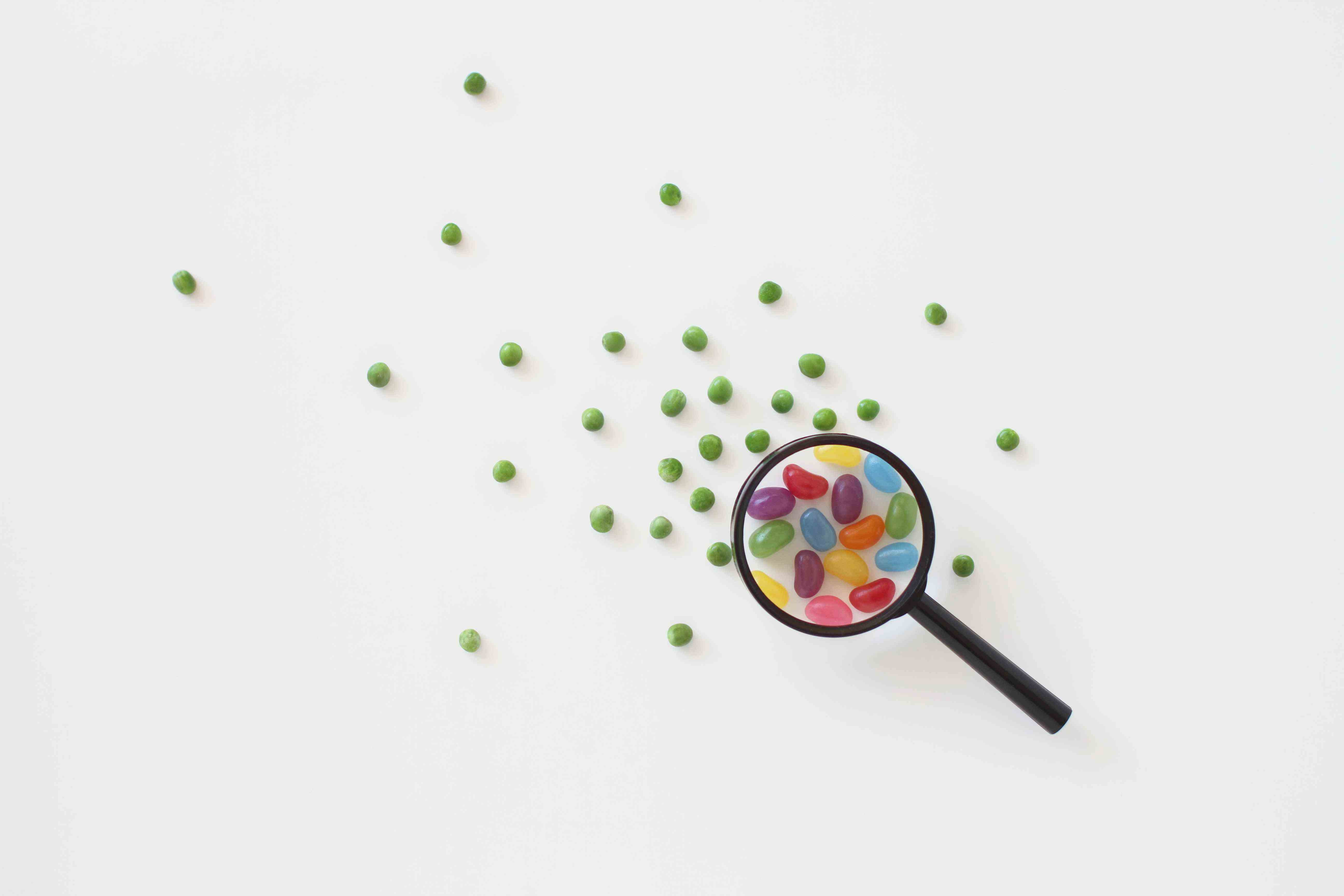 Image de bonbons sous une loupe entourée de pois pour représenter l'examen réglementaire.