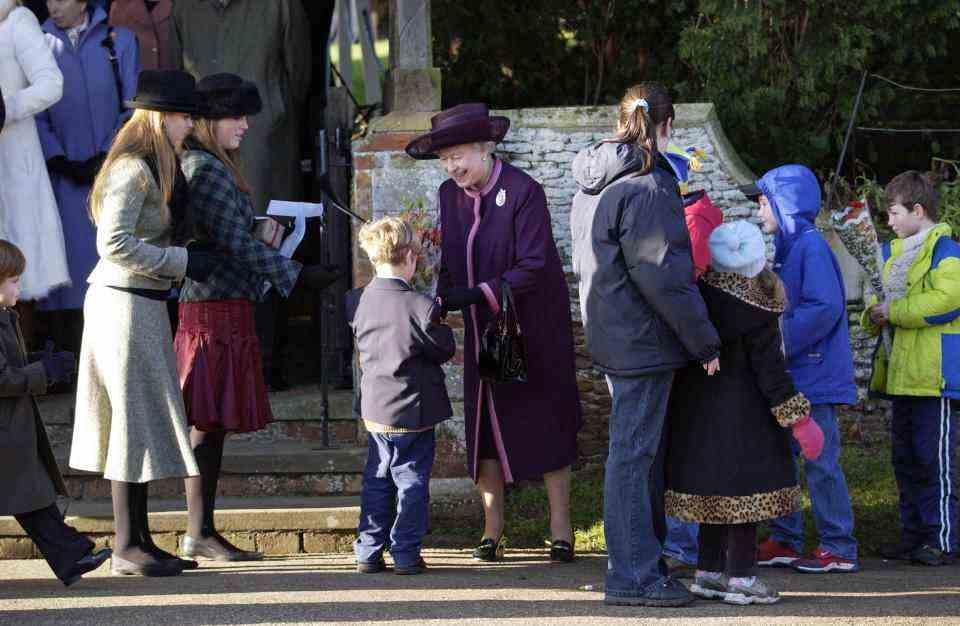 SANDRINGHAM, ROYAUME-UNI - 25 DÉCEMBRE: La princesse Béatrice et la princesse Eugénie attendent d'aider leur grand-mère la reine Elizabeth II avec des fleurs et des cadeaux qu'elle reçoit des enfants de la foule après le service de Noël à Sandringham (Photo de Tim Graham Photo Library via Getty Images)