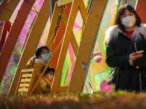 Une femme et un enfant portant des masques faciaux montent sur une balançoire devant un centre commercial rouvert à Pékin.