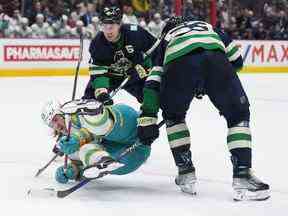 Alexander Barabanov (94) des Sharks tombe devant Brock Boeser (6) et Bo Horvat (53) lors de la deuxième période au Rogers Arena de Vancouver mardi soir.