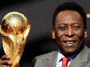 Sur cette photo d'archive prise le 09 mars 2014, la légende du football brésilien Pelé pose avec le trophée de la Coupe du monde de football lors d'une conférence de presse, devant l'Hôtel de Ville à Paris.  (Photo de FRANCK FIFE/AFP via Getty Images)