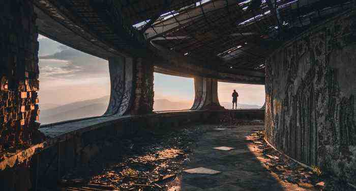 une photo de quelqu'un dans un paysage d'un autre monde, comme un gratte-ciel abandonné depuis longtemps