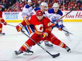 L'ailier gauche des Flames de Calgary Andrew Mangiapane et l'ailier gauche des Oilers d'Edmonton Zach Hyman se battent pour la rondelle au cours de la troisième période au Scotiabank Saddledome.