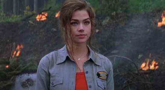 Denise Richards stands at an explosion site, looking annoyed in The World is Not Enough.