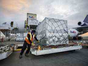 Des travailleurs déchargent une cargaison de vaccins Moderna COVID-19 au hub FedEx de l'aéroport international Pearson de Toronto le 20 mai 2021.