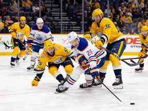 Mattias Janmark (26 ans) des Oilers d'Edmonton tente de contrôler la rondelle contre Roland McKeown (55 ans) et Cole Smith (36 ans) des Predators de Nashville lors de la deuxième période au Bridgestone Arena le 13 décembre.