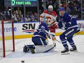 Le gardien de but des Maple Leafs de Toronto Matt Murray, le défenseur Justin Holl et l'attaquant des Flames de Calgary Nazem Kadri regardent un rebond passer à côté du filet samedi soir.  USA AUJOURD'HUI Sports