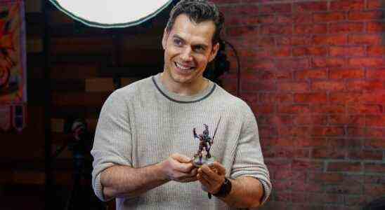 Henry Cavill holding a Warhammer figure.