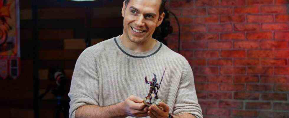 Henry Cavill holding a Warhammer figure.