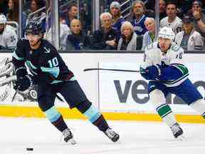 Le centre de Seattle Kraken Matty Beniers (10) patine avec la rondelle devant l'ailier gauche des Canucks de Vancouver Tanner Pearson (70) au cours de la deuxième période au Climate Pledge Arena en octobre.