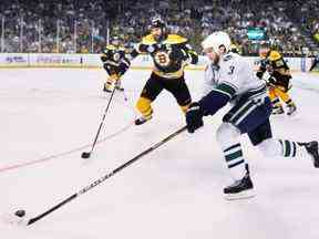 Les Canucks de Vancouver Kevin Bieksa (à droite) tente de porter la rondelle au filet après les Bruins de Boston Zdeno Chara (au centre) au cours de la première période du match 4 de la finale de la Coupe Stanley 2011 de la LNH au TD Garden de Boston, MA, le 8 juin 2011. Canucks mener la série de sept matchs 2-1.