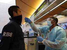 Scott Fujii reçoit un test de coronavirus rapide de 24 heures par l'infirmière Caren Williams au terminal international Tom Bradley de l'aéroport de LAX afin qu'il puisse se rendre à Hawaï pour voir sa famille, à Los Angeles, le 23 novembre 2020.