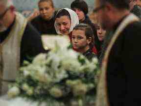 Galyna Legenkovska (en foulard) et ses enfants regardent le cercueil avec sa fille Mariia être amené devant l'église lors d'un service commémoratif à la cathédrale orthodoxe ukrainienne Sainte-Sophie mardi.