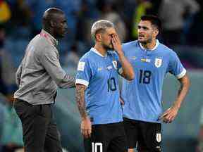 Le milieu de terrain uruguayen # 10 Giorgian De Arrascaeta (C) et l'attaquant uruguayen # 18 Maximiliano Gomez (L) réagissent alors que l'entraîneur ghanéen Otto Addo les approche à la fin du match de football du groupe H de la Coupe du monde Qatar 2022 entre le Ghana et l'Uruguay à l'Al-Janoub Stade d'Al-Wakrah, au sud de Doha, le 2 décembre 2022.