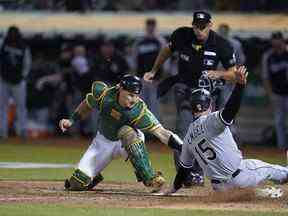 Le receveur d'Oakland Athletics, Sean Murphy, à gauche, tente de taguer Adam Engel des Chicago White Sox, qui a marqué le point égalisateur lors de la neuvième manche d'un match de baseball à Oakland, en Californie, le 9 septembre 2022.