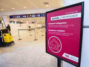 Un panneau rappelle aux passagers arrivant de se mettre en quarantaine contre le COVID-19 à l'aéroport Trudeau de Montréal, le 19 février 2021.