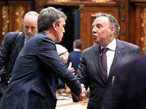 Le premier ministre François Legault, à droite, échange ses salutations avec le chef par intérim du Parti libéral du Québec, Marc Tanguay, avant la fin de l'année à l'Assemblée nationale vendredi.