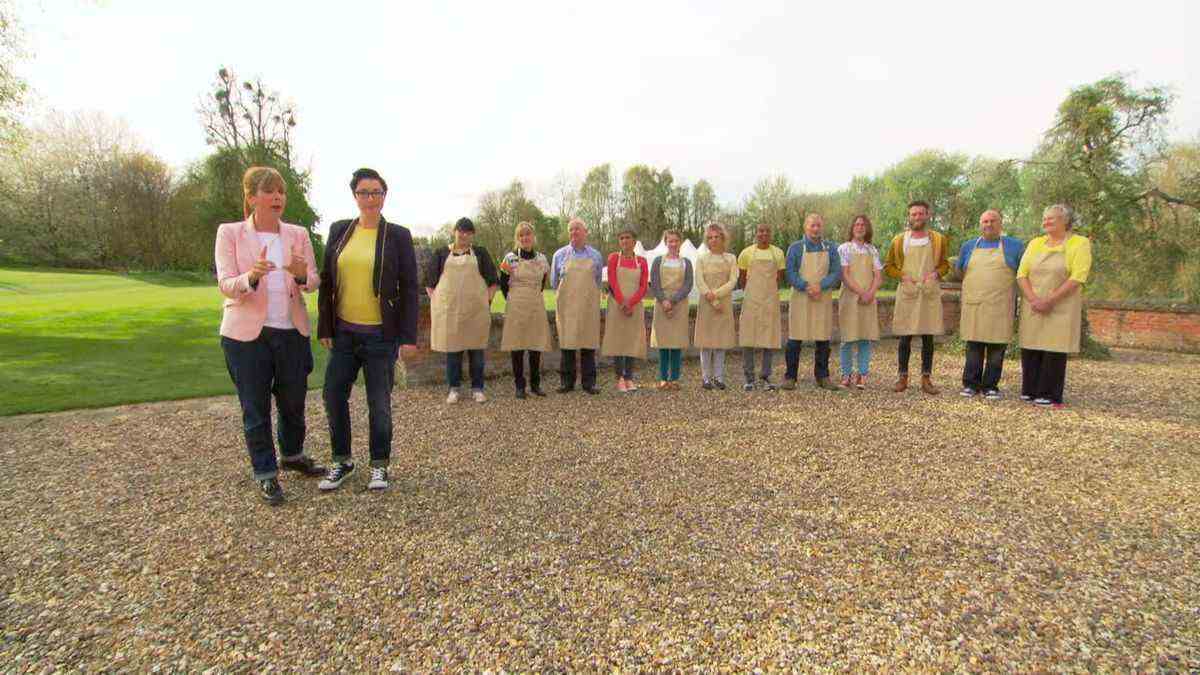 Mel et Sue se tiennent à gauche, devant les boulangers de la saison 5 de Great British Bake Off, faisant la queue à l'extérieur.