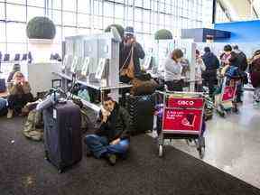 Les passagers confrontés à des retards et des annulations font la queue pour téléphoner pour contacter les compagnies aériennes au niveau des départs du terminal 1 de l'aéroport international Pearson de Toronto le vendredi 23 décembre 2022.