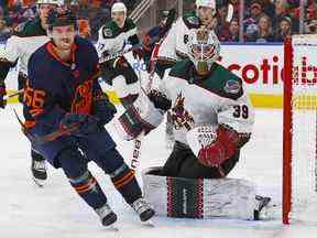 L'attaquant des Oilers d'Edmonton Kailer Yamamoto et le gardien des Coyotes de l'Arizona Connor Ingram cherchent une rondelle libre au cours de la troisième période à Rogers Place le 7 décembre 2022.