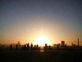 Les gens regardent le lever du soleil depuis le sommet de Primrose Hill à Londres, en Grande-Bretagne.