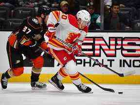 L'attaquant des Flames de Calgary Blake Coleman (20 ans) déplace la rondelle devant l'attaquant des Ducks d'Anaheim Mason McTavish (37 ans) lors de la première période au Honda Center le 23 décembre 2022 à Anaheim, Californie, États-Unis.