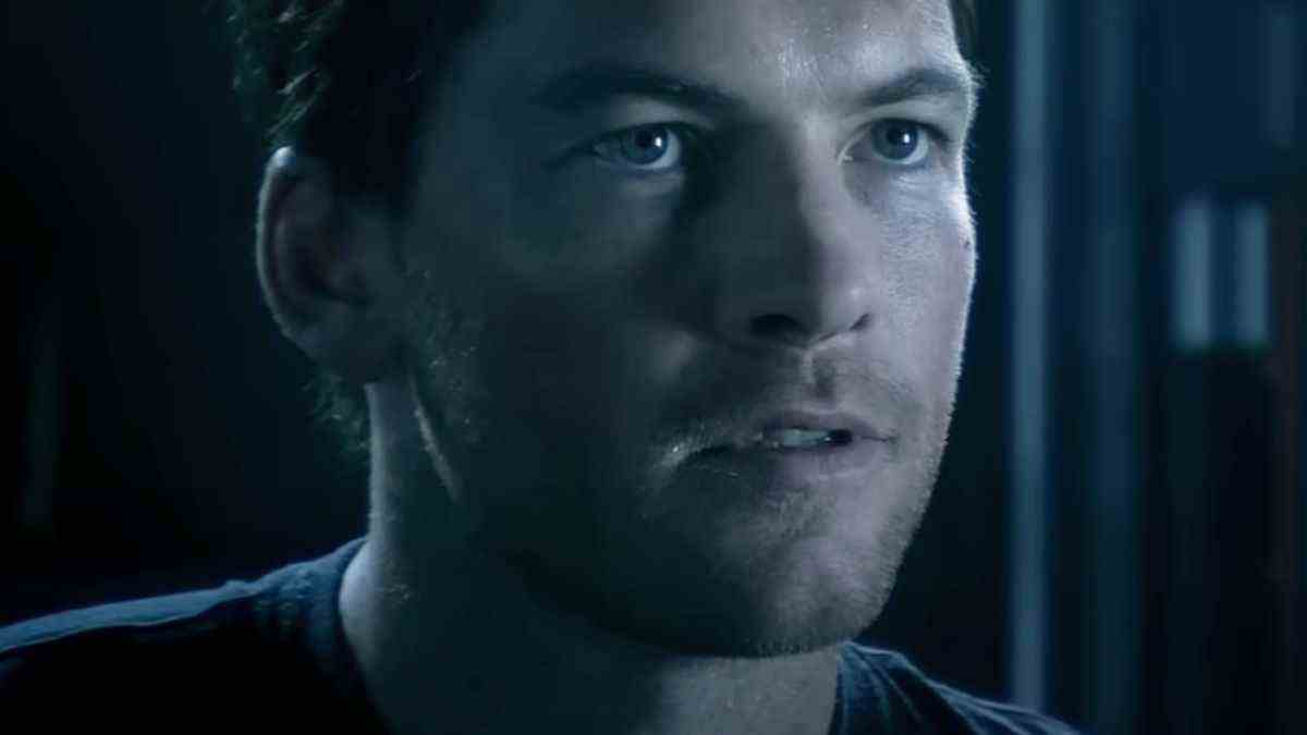 Sam Worthington looking forward with determination in a dark room in Avatar.